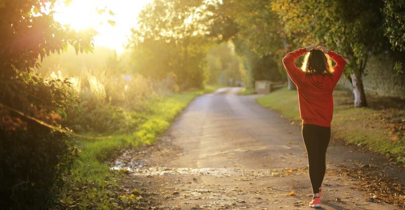 Woman walking at sunrise on a country road